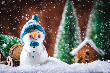 Merry Christmas and happy New Year composition with copy space. Little snowman carries Christmas tree from fairy forest to home. Winter festive backgroundの写真素材