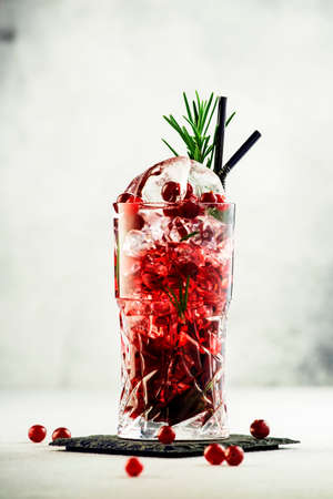 Cranberry cocktail with ice, rosemary and berries in highball glass, gray background, copy spaceの写真素材