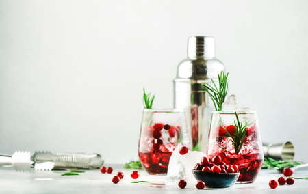 Cranberry cocktail or mocktail with ice, rosemary and red berries in tumbler glass, gray background, copy spaceの写真素材