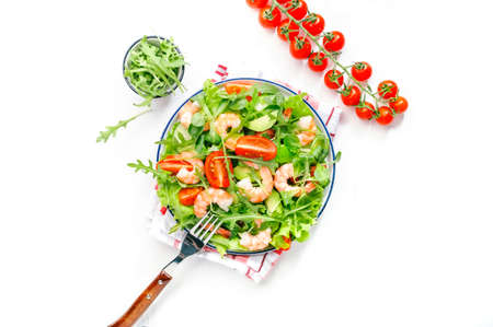 Fresh shrimp salad with tomatoes, lettuce, arugula, avocado, cucumber and lemon dressing on white background. Healthy eating, clean food concept. Top viewの写真素材