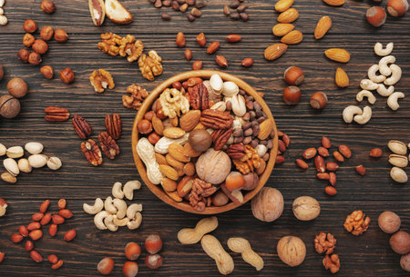 Assortment of nuts in bowls. Cashews, hazelnuts, walnuts, pistachios, pecans, pine nuts, peanuts, macadamia, almonds, brazil nuts. Food mix on wooden background, top view, copy spaceの写真素材