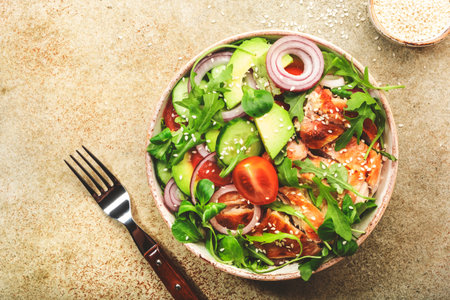 Fresh salad with grilled chicken, cherry tomatoes, arugula, red onion, avocado, sesame seeds and lemon oil dressing. Healthy food concept. Top view. Copy spaceの写真素材