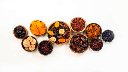 Healthy food snack: dried fruits, natural sun dried organic mix of dried apricots, figs, raisins, dates, cranberries, cherries, goji berries, prunes in bowls on white background, top viewの写真素材