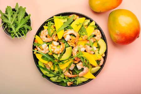 Summer Salad with Mango, Shrimps and Avocado, Walnut, Spinach and Arugula. Healthy Eating food concept Top view, pink backgroundの写真素材