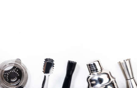 Steel bar tools and accessories for making cocktail. Shaker, jigger, strainer, spoon, tongs, muddler. Alcohol drink and beverages preparation concept. White background, top view, copy spaceの写真素材