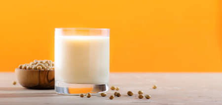 Soy milk and soy bean on orange background. Non-dairy milk concept. Vegan Drink. Copy space bannerの写真素材