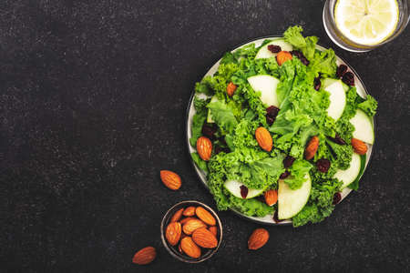 Kale salad with dried cranberry, green apples and almonds. Vegan healthy food, top view, black kitchen tableの写真素材