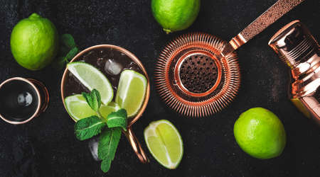 Moscow Mule. Preparation cocktail with ginger beer, vodka, lime and ice. Copper bar tools. Black bar counter. Top viewの写真素材
