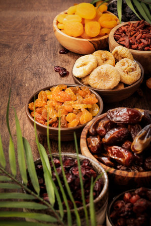 Healthy food snack: sun dried organic mix of dried fruits: apricots, figs, raisins, dates, and other on wooden table, top viewの写真素材
