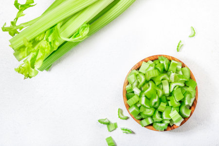 Chopped green celery in bowl, white table background, top view, copy spaceの写真素材