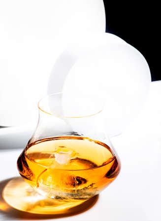 Whiskey, scotch or bourbon glass with ice on black and white background with geometric cubes and circles. Contemporary still lifeの写真素材