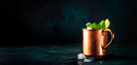 Moscow mule alcoholic cocktail in copper mug with lime, ginger beer, vodka and mint. Blue table, copper bar toolsの写真素材
