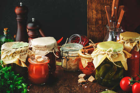 Fermented, pickled, marinated preserved vegan food. Organic vegetables and fruits in jars with spice and herbs on black kitchen table. Homemade cunning conceptの写真素材