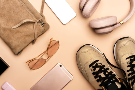 Girls hipster summer nude pink stuff and accessories: bag, sneakers, phone, headphones, sunglasses on pale pink background, top viewの写真素材