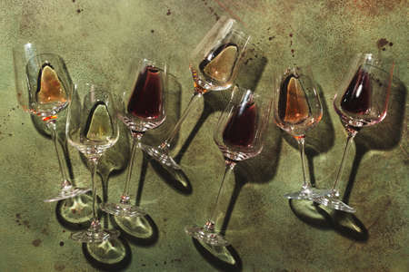 Red, rose and white wine in glasses on rusty green background, top view. Wine bar, shop, winery, wine tasting concept. Hard light and harsh shadowsの写真素材