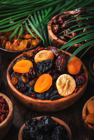 Dried fruits bowl. Healthy food snack: sun dried organic mix of apricots, figs, raisins, dates and other on wooden table, top viewの写真素材