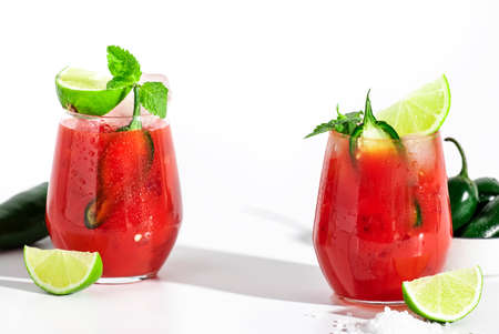 Spicy cocktail with vodka, tomato juice, jalapeno pepper, ice, lime and salt, white background, hard light, negative spaceの写真素材