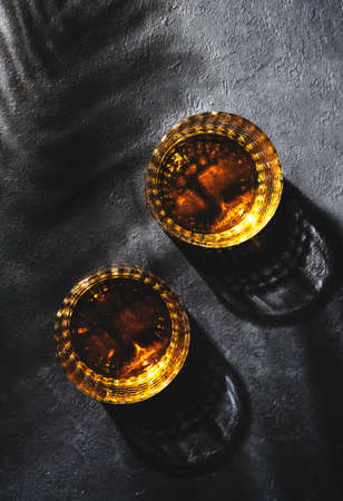 American bourbon whiskey in glasses and bottle, black background with shadow pattern and negative spaceの写真素材