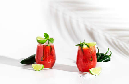 Spicy cocktail with vodka, tomato juice, jalapeno pepper, ice, lime and salt, white background, hard light, negative spaceの写真素材