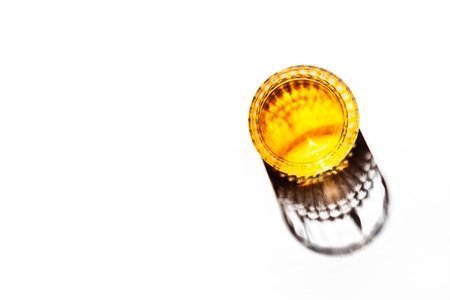 American bourbon whiskey in glass, white background with shadow pattern and negative space. Hard...