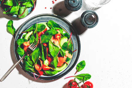 Salmon avocado salad, beet leaves, radicchio, tomatoes, lemon and olive oil dressing for keto and low card diet. Gray background, top viewの写真素材