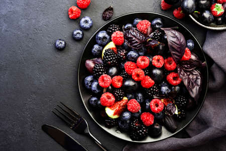 Autumn blue and black berries fruit vegan salad: blueberries, blackberries, grapes, figs and purple...