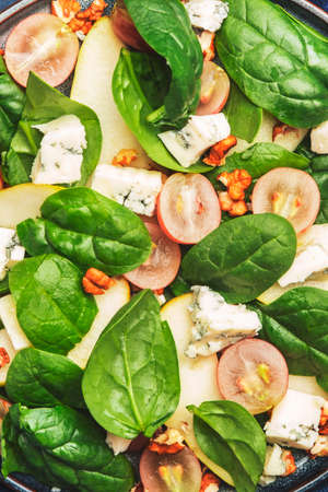 Salad with pear, blue cheese, spinach, grapes, walnuts on blue background, top view, copy spaceの写真素材