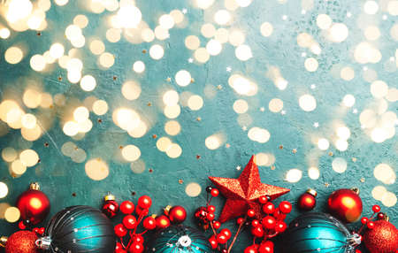 Blue Christmas or New Year background with red and blue Christmas balls, berries, garland lights, golden bokeh top viewの写真素材