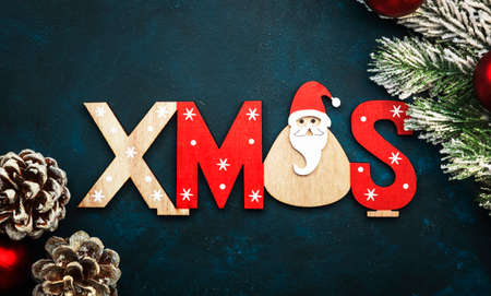 Blue Christmas or New Year background with red Christmas balls, fir branches, pine cones and inscription Xmas, top viewの写真素材