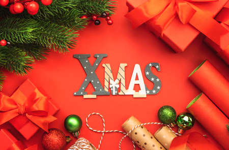 Merry Christmas and Happy New Year red background with boxes, ribbons, bows, wrapping paper, spruce branches and holiday decor. Gift wrapping, Preparation for holidays. Top viewの写真素材