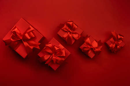 Red background with gift boxes, ribbons, bows. Preparation for holidays. Christmas, Valentines day,...