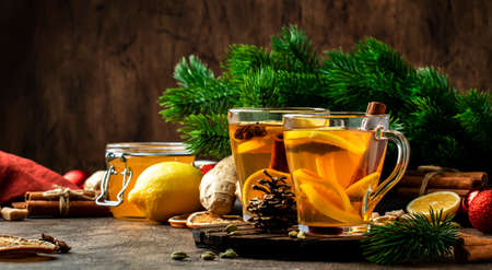 Winter hot healing tea with ginger, honey, lemon and spices in glass cup with steam, rustic wooden background. Christmas table settingsの写真素材