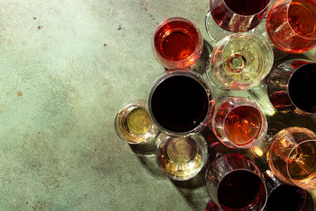 Red, white and rose wines in assortment in glasses on green background, top view. Wine bar, shop,...