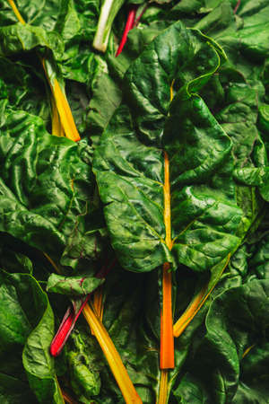 Rainbow swiss chard leaves on rusty background, raw green leaf vegetables, top view, copy space