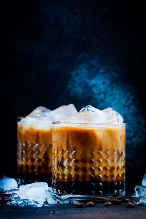 Trendy alcoholic cocktail drink with vodka, coffee liqueur, cream and ice on dark background, copper...
