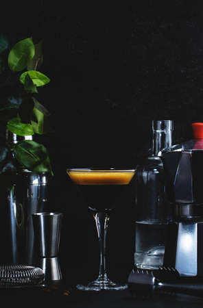 Classic alcoholic cocktail Espresso martini with vodka, coffee liqueur, syrup and ice in glass on dark counter background, bar tools, negative spaceの写真素材