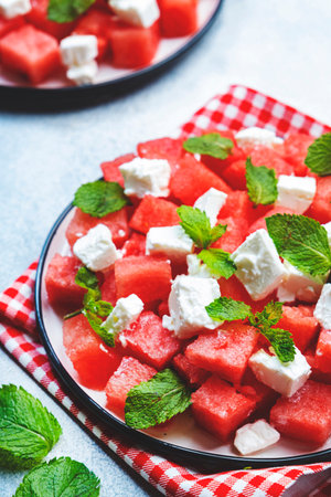 Refreshing summer juicy Watermelon salad with feta cheese and fresh mint, gray table background, top view, copy spaceの写真素材