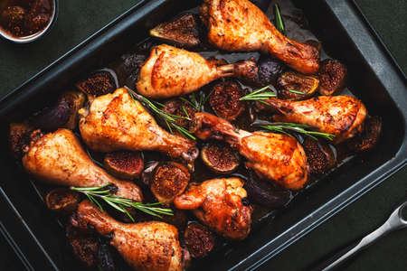 Baked chicken legs, drumsticks with sweet figs and onions in balsamic marinade on black baking...