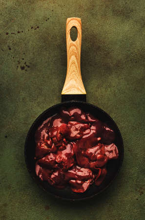 Fresh raw chicken liver in frying pan and ingredients for cooking on concrete green kitchen table, top view, copy spaceの写真素材