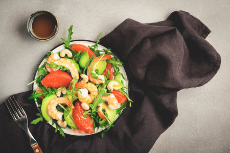 Healthy fresh salad with shrimps, avocado, grapefruit, arugula and cashews. Gray stone kitchen table background, top view, copy spaceの写真素材