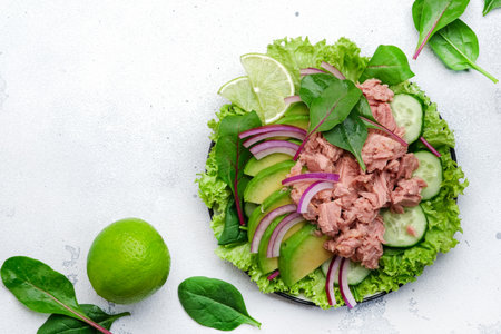 Tuna fish salad with avocado, cucumber, red onion and lettuce. White stone background, top view, copy spaceの写真素材