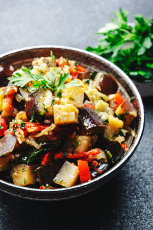 Vegetable stew, saute or caponata. Stewed eggplant with paprika, tomatoes, herbs and spices. Black kitchen table background, top view, copy spaceの写真素材