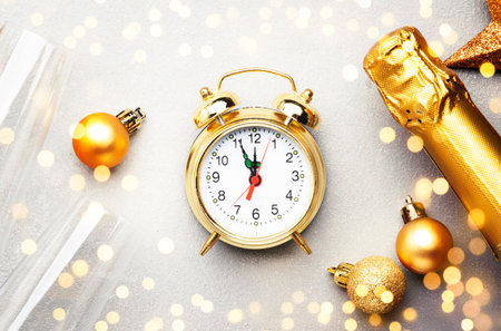 Christmas festive background with champagne bottle and wine glasses, golden christmas balls, alarm clock and decor, top viewの写真素材