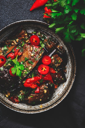 Grilled eggplant with hot red peppers, soy sauce and garlic in asian style, black background, top viewの写真素材
