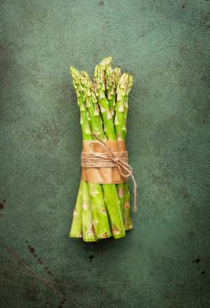 Fresh asparagus bunch on green table background, top view, close-up, space for textの写真素材