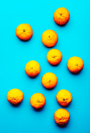 Ripe bright orange tangerines on blue background, fruit pattern. top view, hard lightの写真素材