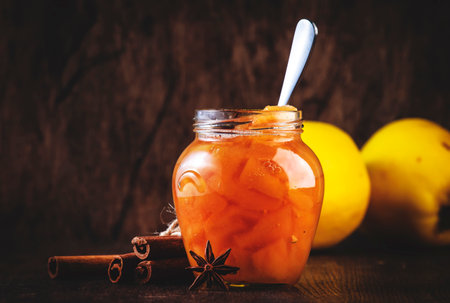 Winter Quince jam or confiture in glass jar with cinnamon and anise on rustic wooden kitchen table...