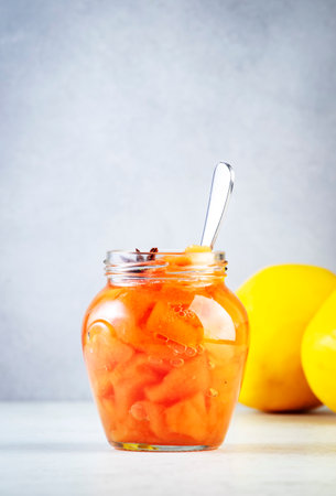 Quince jam or confiture in glass jar with cinnamon and anise on gray kitchen table background, copy spaceの写真素材
