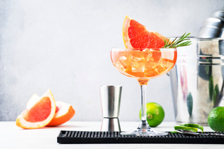 Grapefruit daiquiri alcoholic cocktail with white rum, syrup, fruit juice, lime and ice in garnished margarita glass. gray backgroundの写真素材