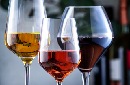 Red, white, rose wine glasses on gray background. Wine bar, shop, tasting concept. Wines and bottles in assortmentの写真素材
